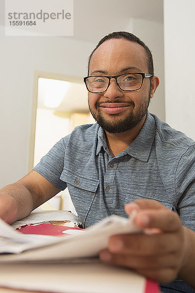 Glücklicher afroamerikanischer Mann mit Down-Syndrom erledigt Papierkram zu Hause