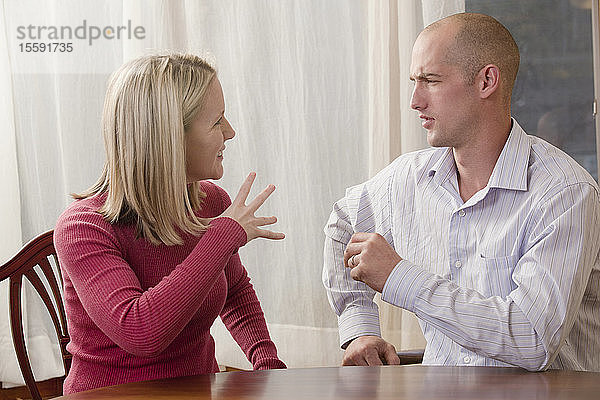 Frau gebärdet das Wort Fine in amerikanischer Zeichensprache  während sie mit einem Mann kommuniziert
