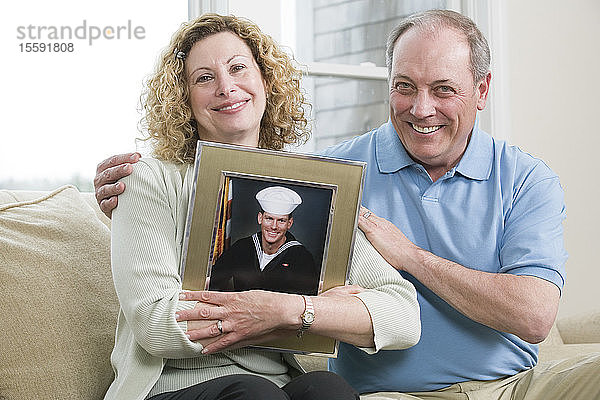 Porträt eines reifen Paares  das ein Bild seines Sohnes hält  der beim Militär arbeitet.