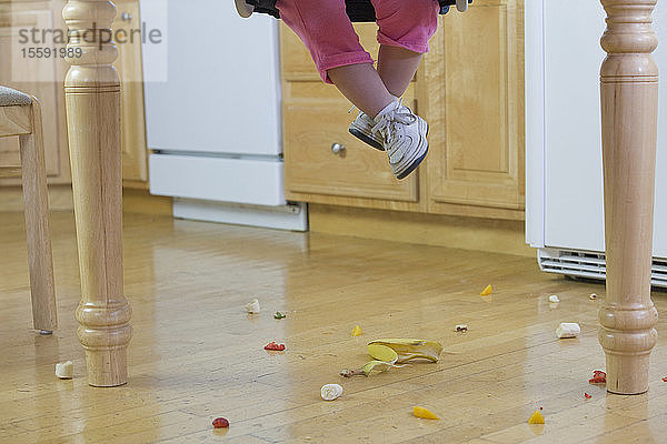 Tiefschnittansicht eines kleinen Mädchens mit verschüttetem Essen auf dem Boden
