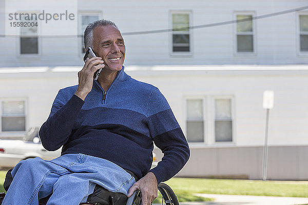Mann mit Querschnittslähmung im Rollstuhl beim Telefonieren