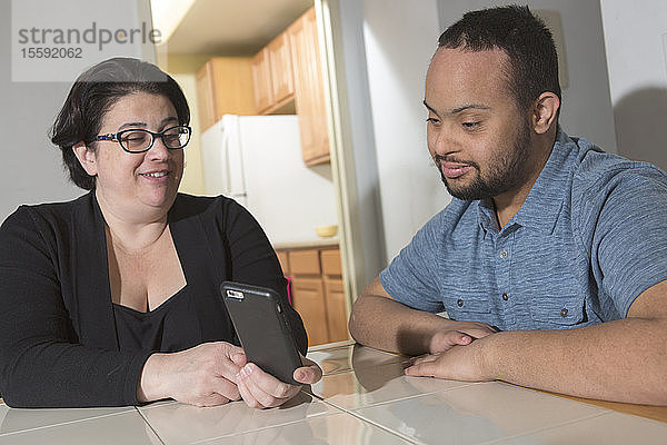Afroamerikanischer Mann mit Down-Syndrom telefoniert mit seiner Mutter zu Hause