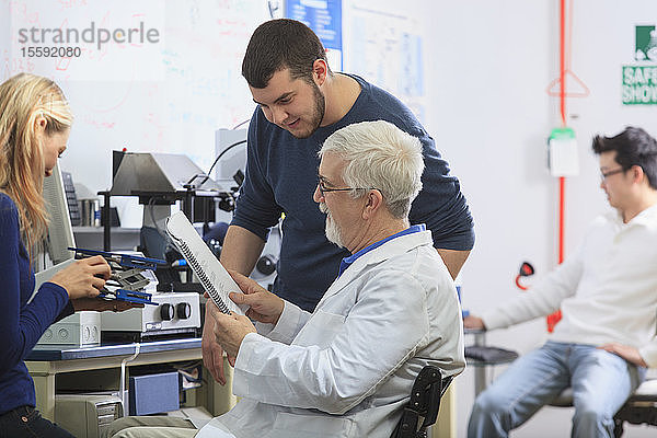 Professor mit Muskeldystrophie und Studenten der Ingenieurswissenschaften verwenden Anleitung zum Aufbau eines Röntgenfluoreszenzexperiments in einem Labor