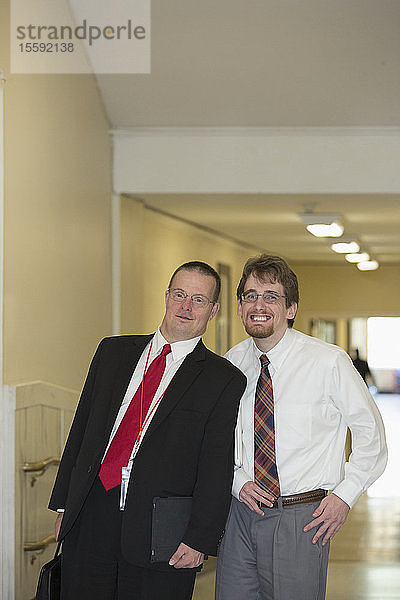 Porträt eines Mannes mit Down-Syndrom  der mit einem Mitarbeiter im Bürokorridor des State Capitol lächelt