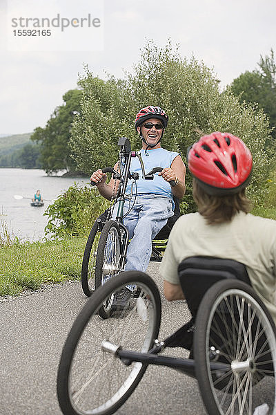 Ein junger Mann mit einer Rückenmarksverletzung und eine junge Frau fahren mit adaptiven Fahrrädern