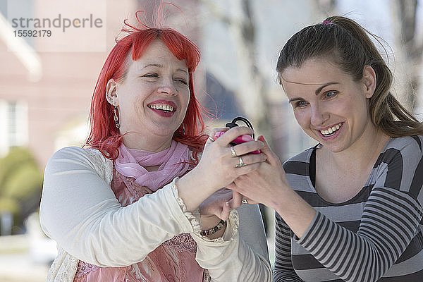 Blinde junge Frauen  die ihre Mobiltelefone als Hilfsmittel nutzen