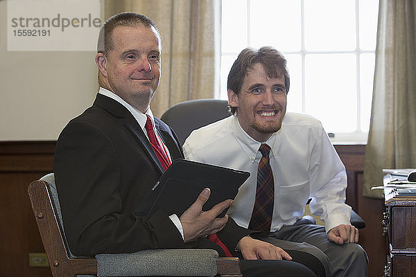 Mann mit Down-Syndrom  der als Assistent der Legislative arbeitet  hält ein Tablet mit seinem Kollegen im Büro im State Capitol