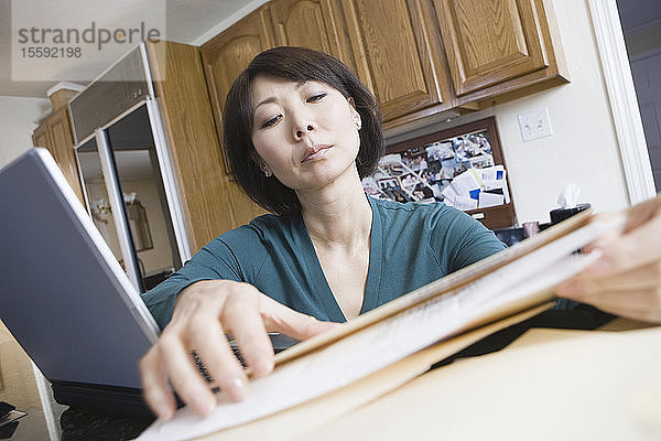 Niedriger Blickwinkel auf eine erwachsene Frau  die zu Hause Papierkram erledigt