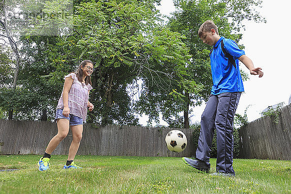 Lernbehindertes Teenager-Mädchen spielt Fußball mit ihrem Bruder