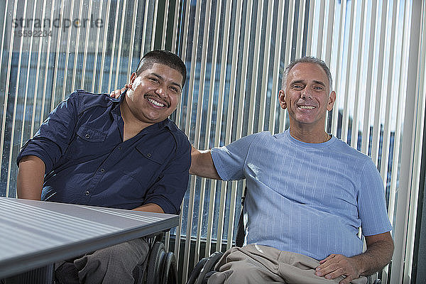 Porträt von zwei Männern mit Rückenmarksverletzungen auf Rollstühlen in einem Büro
