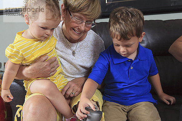 Großmutter mit Beinprothese erlaubt ihren Enkelkindern  mit ihrem Bein zu spielen