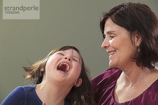 Kleines Mädchen mit Down-Syndrom lacht mit ihrer Mutter