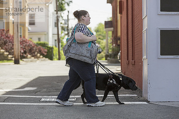 Frau mit Sehbehinderung überquert die Straße mit ihrem Diensthund