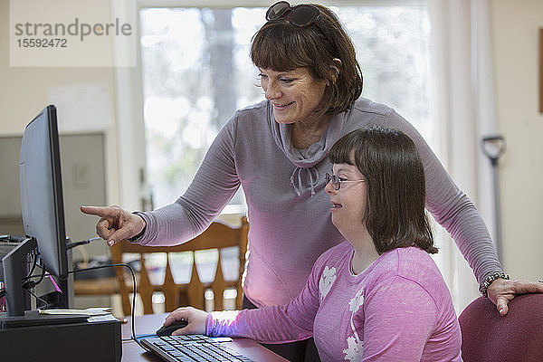 Frau mit Down-Syndrom und ihre Mutter am Computer