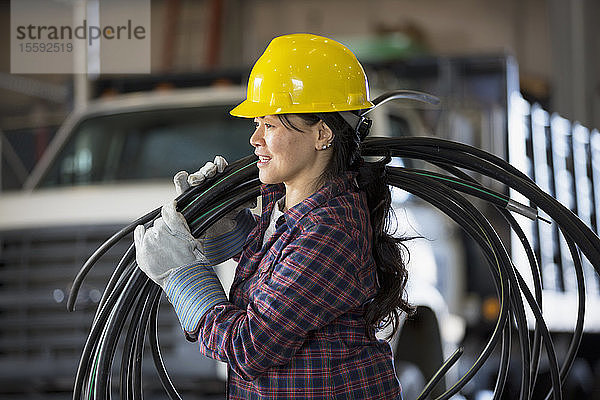 Energietechnikerin mit Stromkabel in der Servicewerkstatt