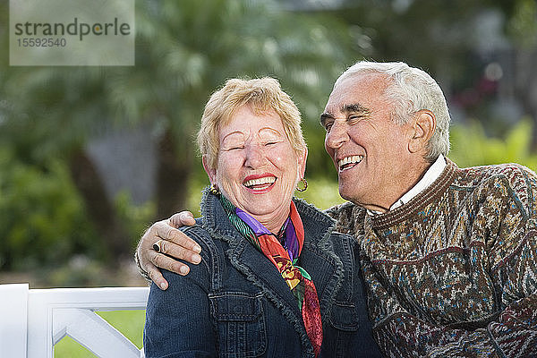 Blick auf ein lächelndes Seniorenpaar in einem Park.