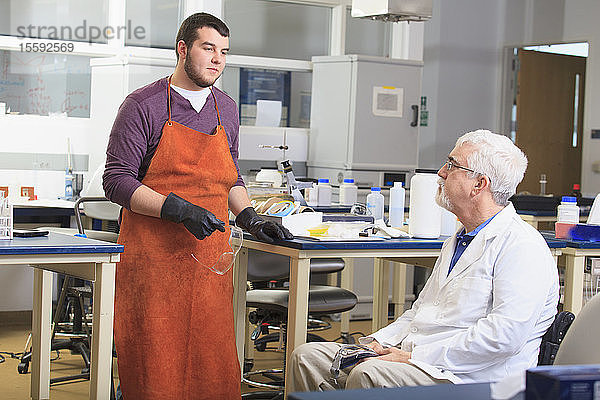 Professor mit Muskeldystrophie berät Ingenieurstudenten in einem Chemielabor