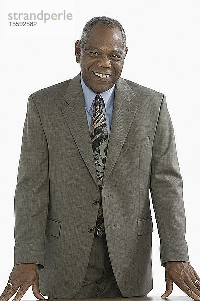 Porträt eines Geschäftsmannes  der am Schreibtisch steht und lächelt