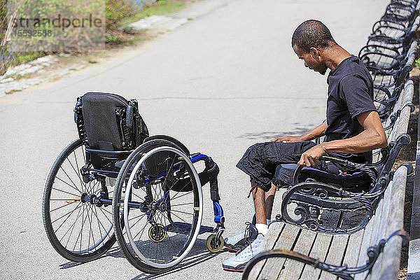 Mann mit Rückenmarkshautentzündung  der sich im Rollstuhl in einem Park ausruht