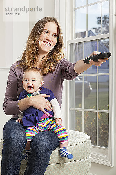 Frau sieht mit lächelndem Baby fern