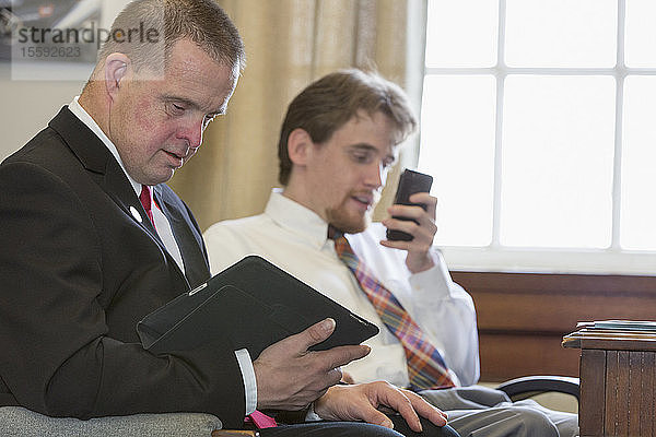Ein Mann mit Down-Syndrom  der als Assistent der Legislative arbeitet  benutzt ein Tablet und telefoniert mit seinem Kollegen im Büro des State Capitol