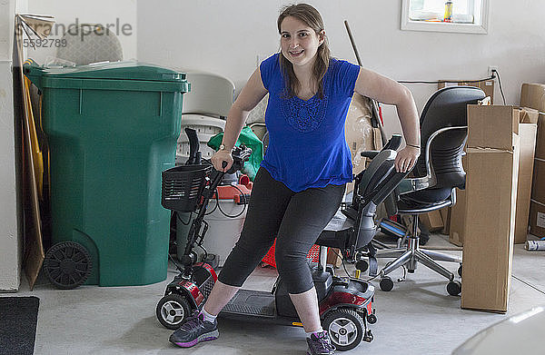 Junge Frau mit Cerebralparese steigt in der Garage auf ihren Motorroller