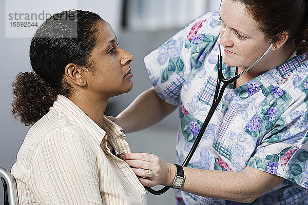 Krankenschwester bei der Untersuchung einer Patientin mit Stethoskop