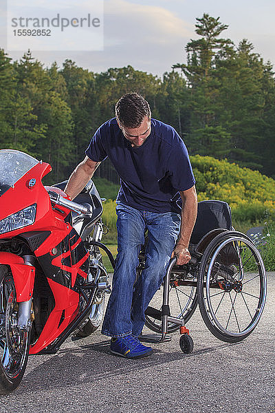 Mann mit Querschnittslähmung wechselt von seinem adaptiven Motorrad in seinen Rollstuhl
