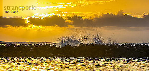 Goldener Sonnenaufgang über dem Lydgate Beach und dem Meer an der Küste von Kauai mit einem Wellenbrecher als Silhouette; Kapaa  Kauai  Hawaii  Vereinigte Staaten von Amerika