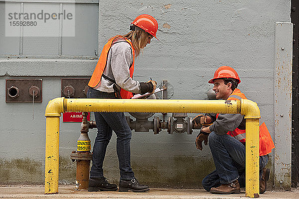 Verfahrenstechniker beim Ablesen von Zählern in der Nähe der Pipeline