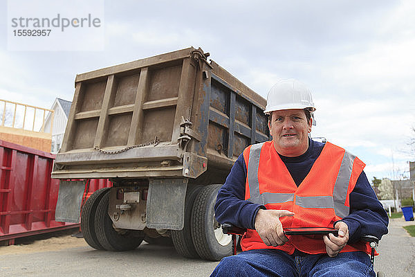 Bauingenieur mit Querschnittslähmung hält Tablette auf der Baustelle