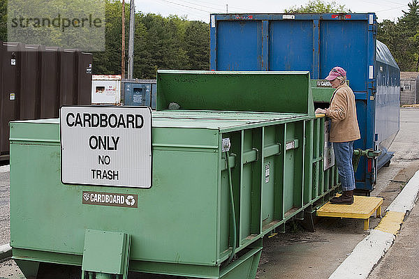 Frau beim Recyceln in der Recyclingpresse von Cardboard Only  die mit einem Container verbunden ist