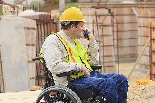 Bauleiter mit Querschnittslähmung inspiziert mit Walkie Talkie Betonfundamentformen