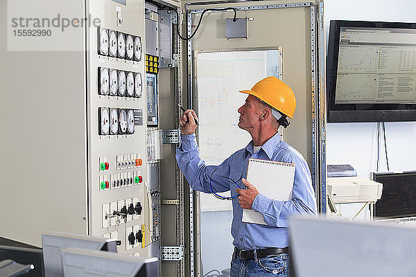Elektroingenieur bei der Inspektion der Kraftwerkssteuerung im zentralen Betriebsraum des Kraftwerks