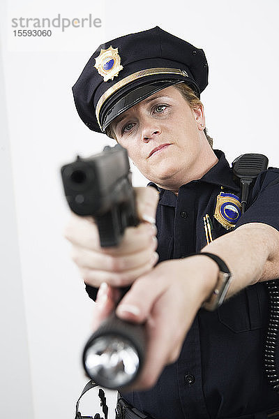Eine Polizistin zeigt auf eine Pistole und hält eine Taschenlampe.