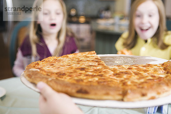 Blick auf zwei Mädchen  die sich eine Pizza ansehen.
