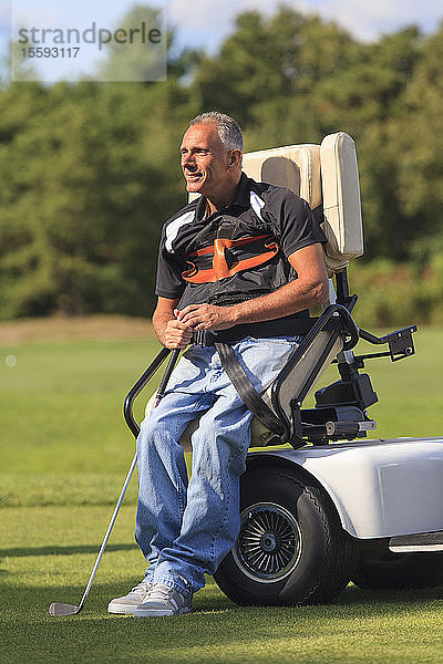 Mann mit Rückenmarksverletzung in einem adaptiven Wagen beim Golfspielen