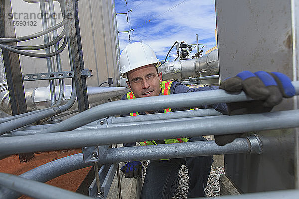 Wirtschaftsingenieur bei der Prüfung einer elektrischen Leitung an einem Brennstofftank in einem Kraftwerk