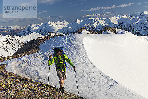 Ein Wanderer überquert im Frühsommer einen verschneiten Bergrücken in der Alaska Range; Alaska  Vereinigte Staaten von Amerika