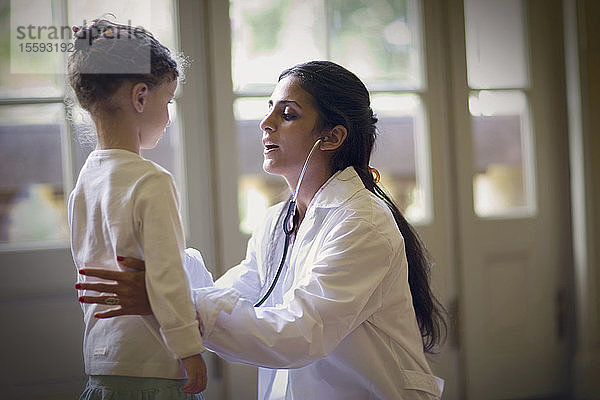 Blick auf eine Ärztin  die ein kleines Mädchen untersucht