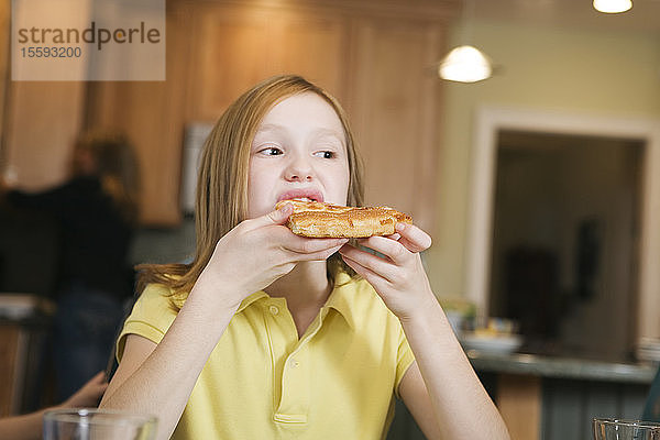Blick auf ein Mädchen  das eine Pizza isst.