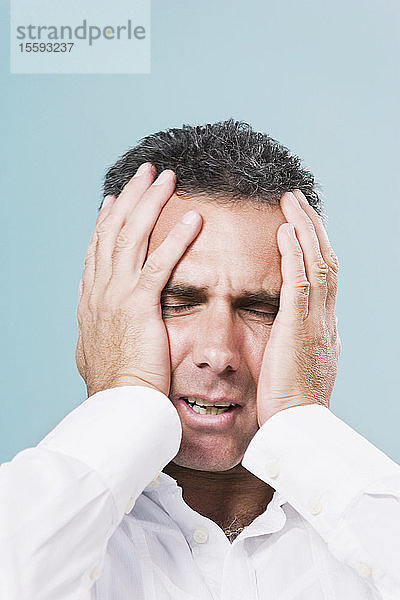 Nahaufnahme eines erwachsenen Mannes  der unter Kopfschmerzen leidet