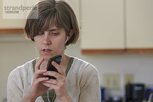 Eine blinde Frau benutzt Ohrstöpsel  um ihr Mobiltelefon zu hören