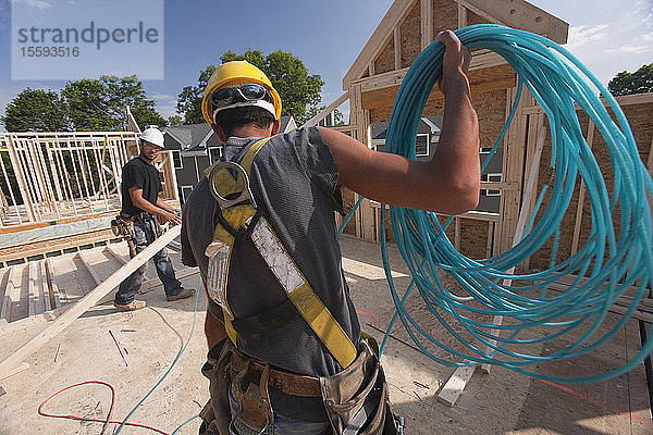 Zimmermann beim Abwickeln eines Luftschlauchs im zweiten Stock eines im Bau befindlichen Hauses