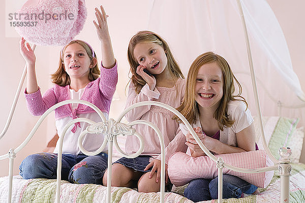 Blick auf drei süße Mädchen  die auf dem Bett spielen.