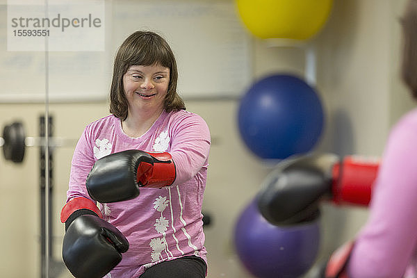 Mädchen mit Down-Syndrom trainiert mit Boxhandschuhen