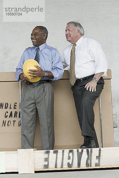 Zwei Ingenieure stehen neben einem Karton und lächeln