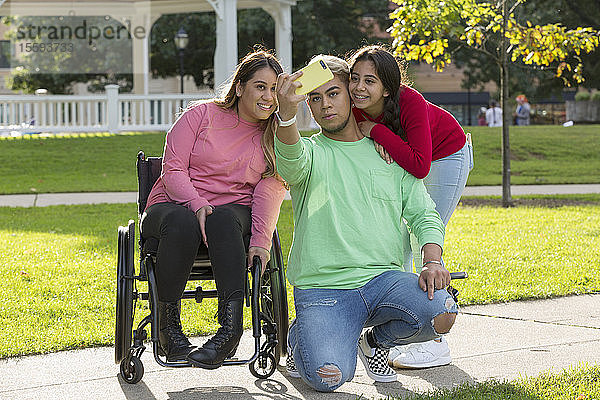 Drei Freunde machen ein Selfie  einer mit einer Rückenmarksverletzung