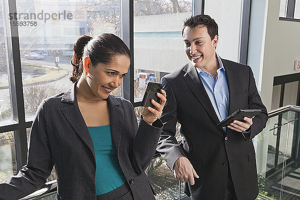 Geschäftspaar im Büro mit Blick auf Tablet und Smartphone