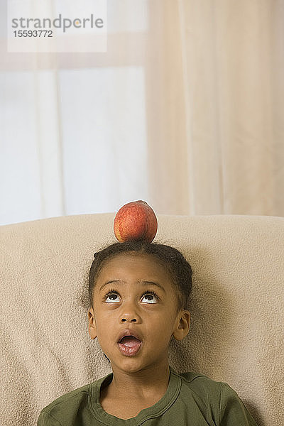 Hispanisches Mädchen balanciert einen Pfirsich auf ihrem Kopf